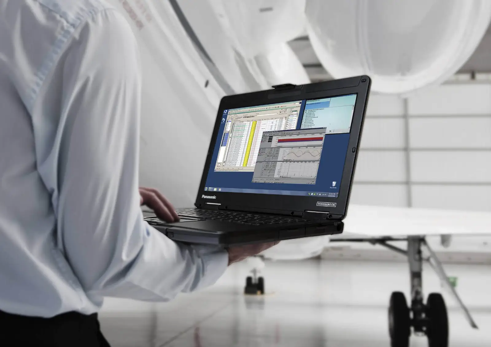 Technician holding a Panasonic Toughbook in an aircraft hangar