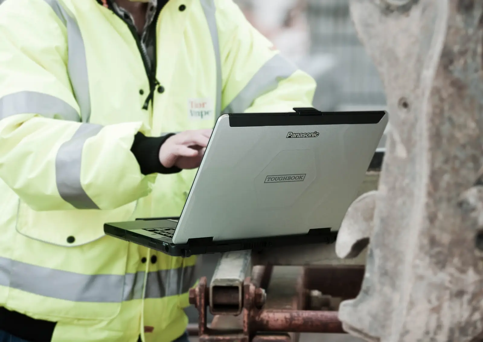 Construction worker in a hi-vis jacket using a Panasonic Toughbook on site